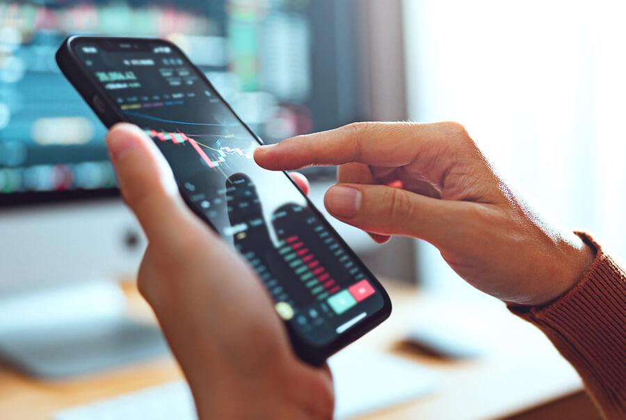 Close up of person using cell phone to track crypto currency
